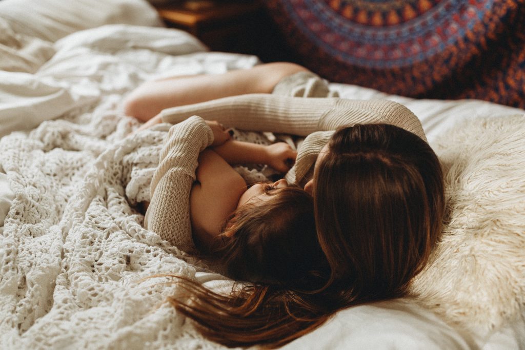 Image of a woman lying down embracing a child taken by Melanie Grace