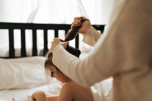 Image of a woman styling a child's hair taken by Melanie Grace
