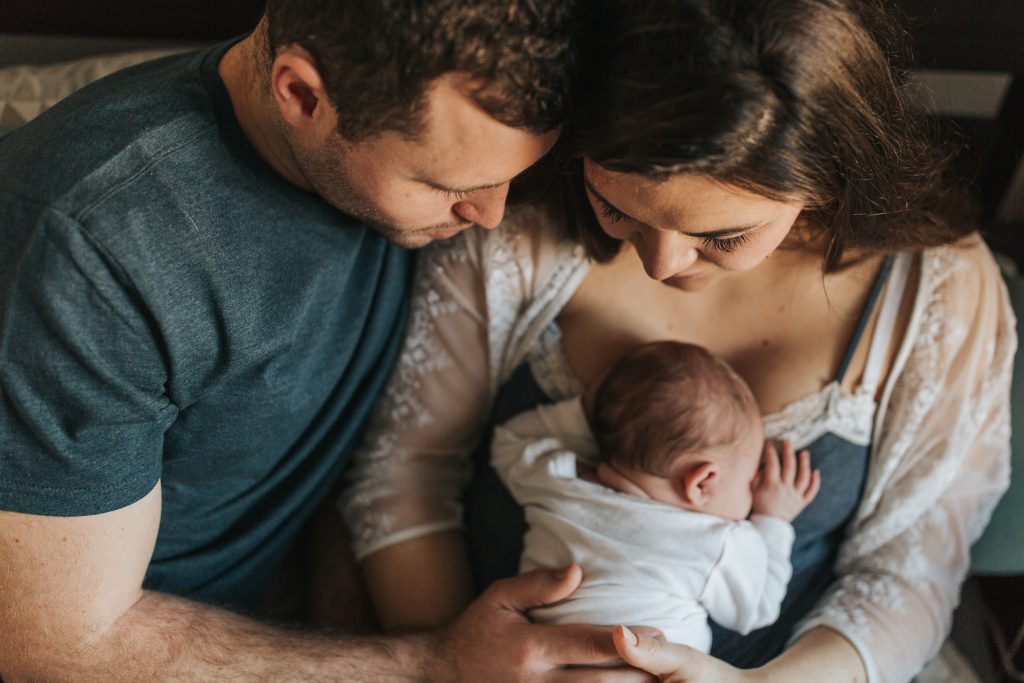 A photo of a couple embracing holding a baby taken by Melanie Grace 