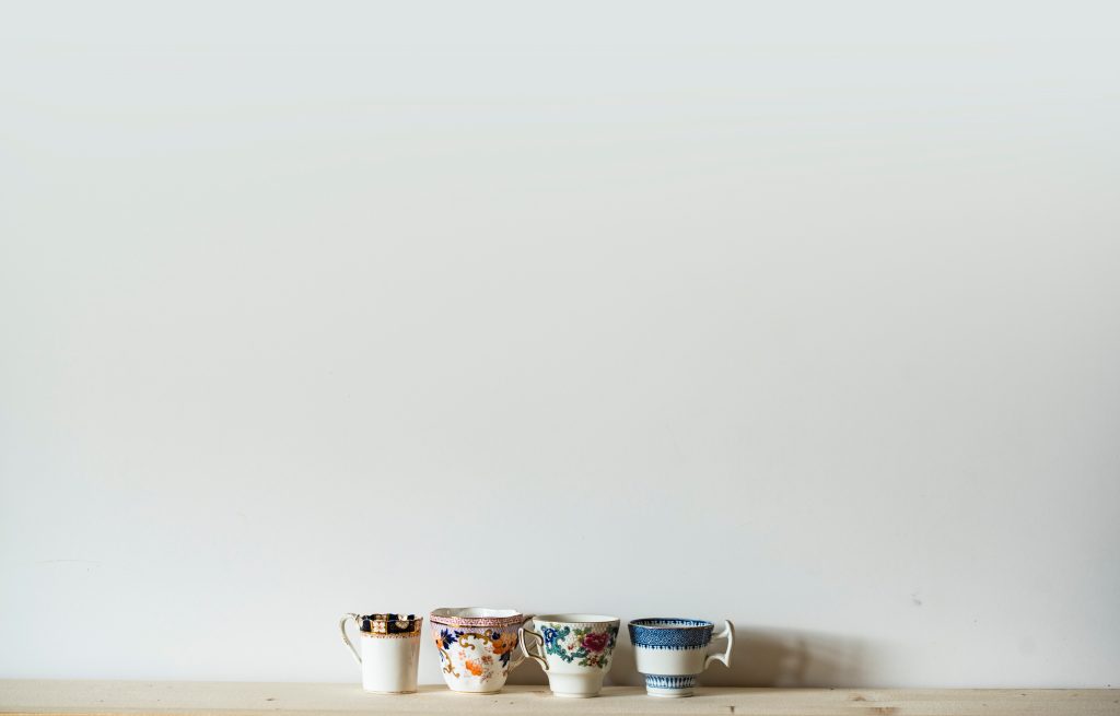 A line of teacups on a shelf against a white background