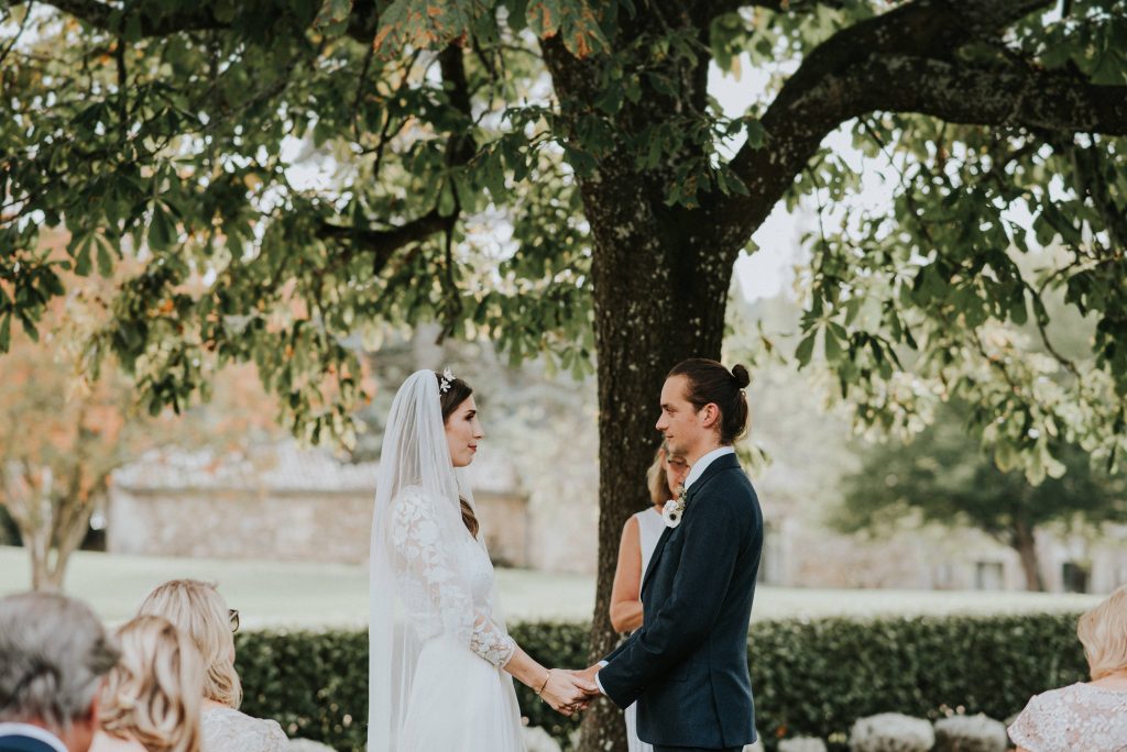 Image of a bride and groom holding hands in front of guests taken by Fern Edwards